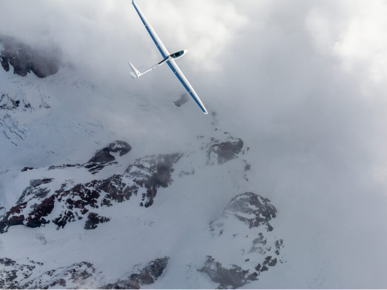 Glider banking above snowy ridges