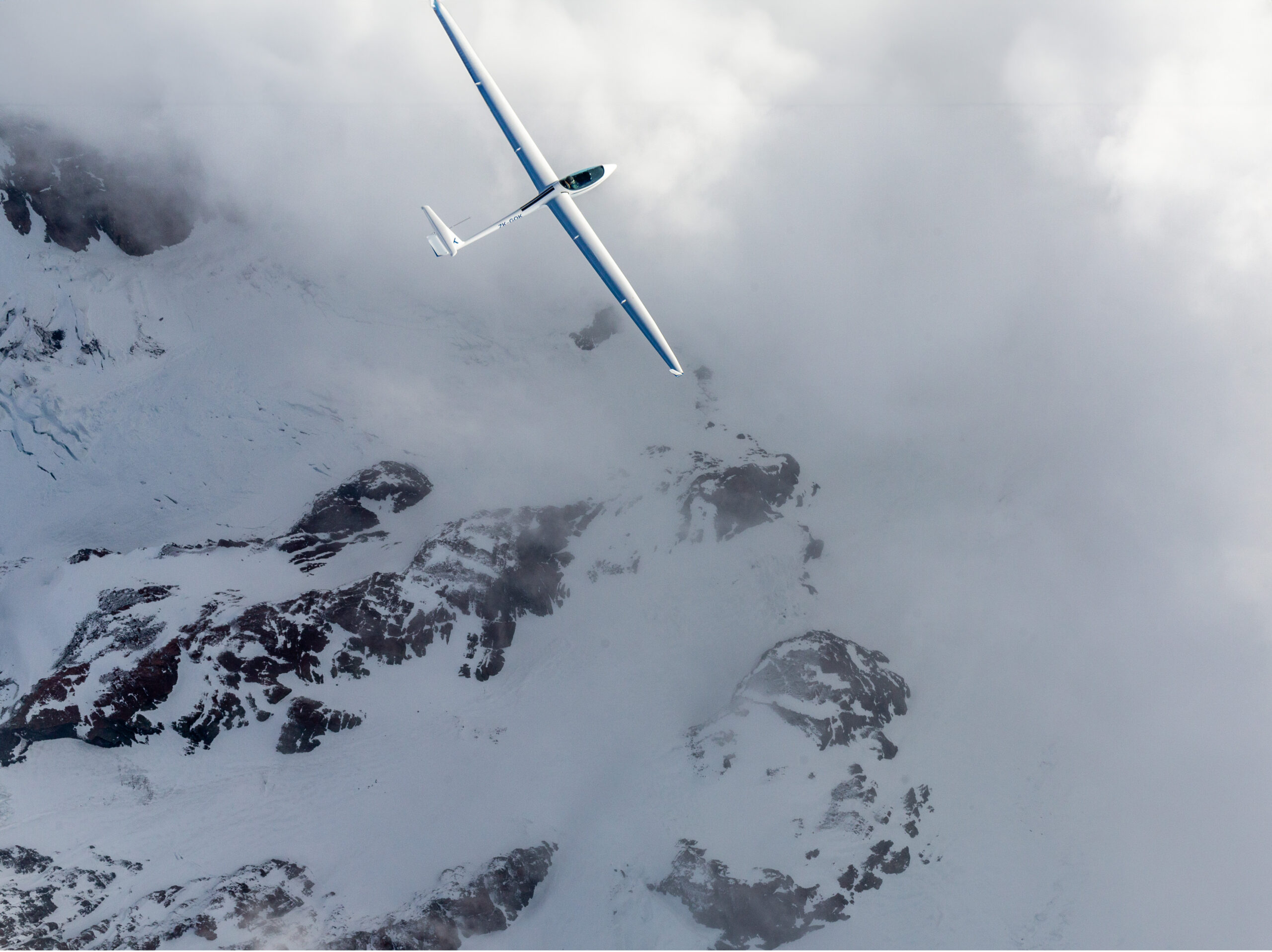 Glider banking above snowy ridges